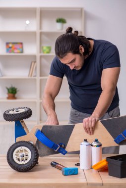Kaykay tamir eden genç bir erkek tamirci.