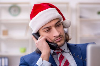Noel arifesinde ofiste çalışan genç bir erkek işçi.