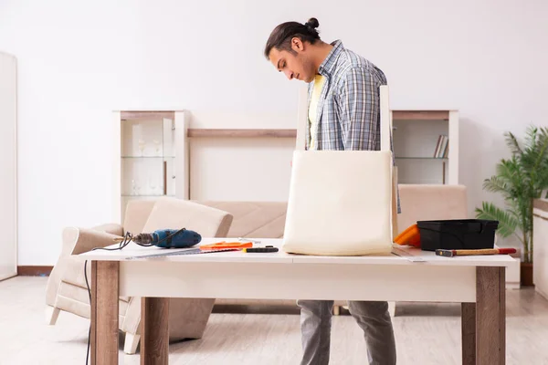 Young male carpenter repairing furniture at home