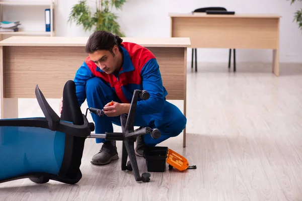 Young male contractor repairing furniture in the office