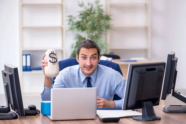 Joven empleado masculino sosteniendo bolsa de dinero en la oficina —  Fotos de Stock