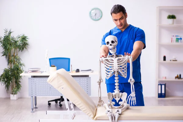 Junge männliche Arzt und Skelett auf der Couch — Stockfoto