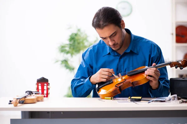 Young male repairman repairing violin