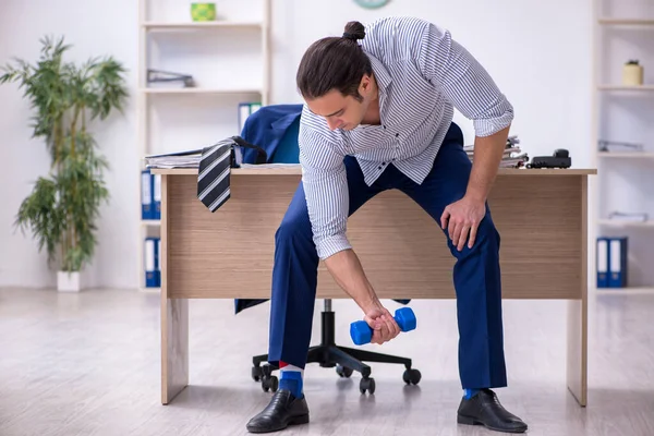 Young handsome male employee doing exercises in the office — Stock Photo, Image