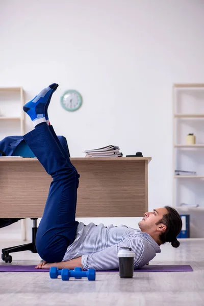 Junge hübsche männliche Angestellte machen Übungen im Büro — Stockfoto