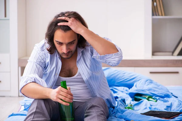 Молодой мужчина алкоголик в спальне — стоковое фото