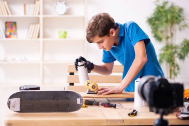 Çocuk kaykayı tamir ediyor ve blogu için video kaydediyor.