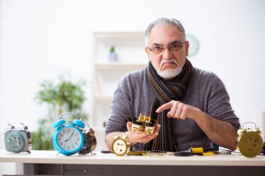 Atölyede çalışan yaşlı bir erkek saatçi.