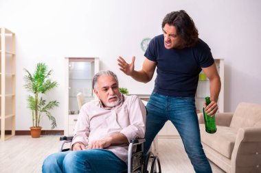 Tekerlekli sandalyedeki yaşlı adam ve genç kötü bakıcı.