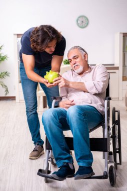 Tekerlekli sandalyedeki yaşlı adam ve genç kötü bakıcı.