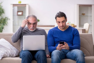 Baba oğul kanepede bilgisayar başında oturuyor.