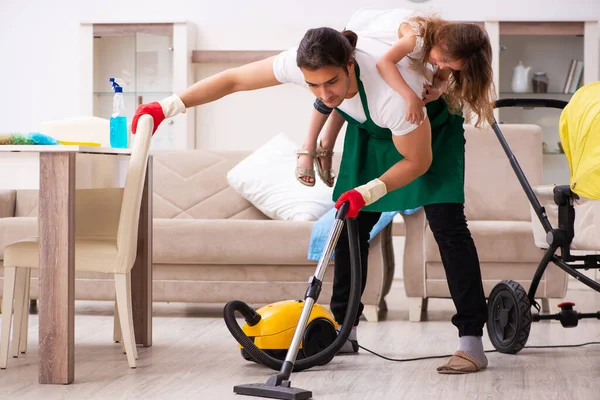 Jovem empreiteiro limpando a casa com sua filha pequena — Fotografia de Stock