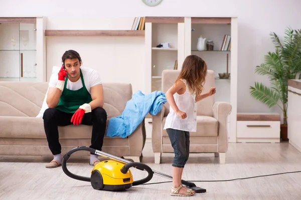 Jovem empreiteiro limpando a casa com sua filha pequena — Fotografia de Stock