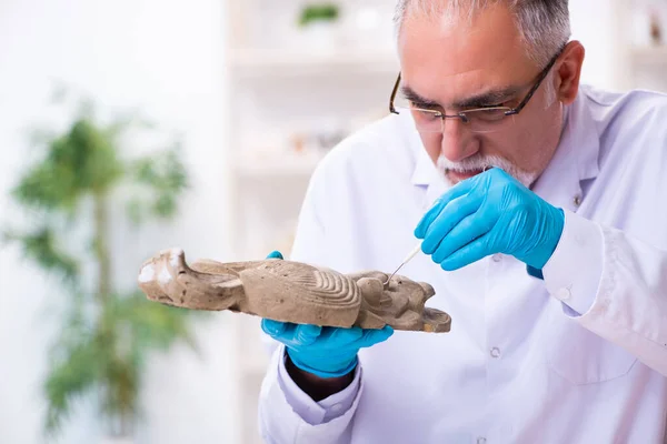 Starší archeolog studující starověké africké kamenické masky — Stock fotografie