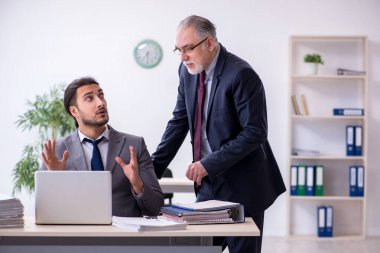 Eski patron ve genç asistanı ofiste çalışıyor.