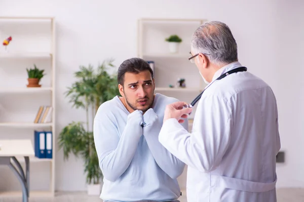 Young sick man visiting old doctor