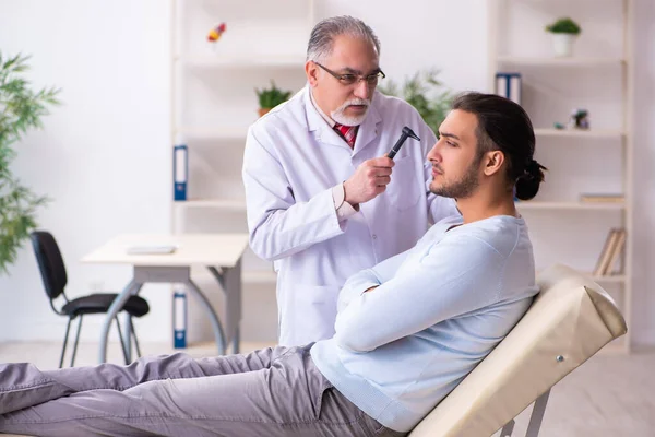 Ung sjuk man besöker gammal läkare otolaryngologist — Stockfoto