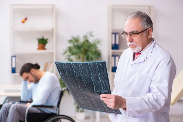 Young man in wheel-chair and old doctor radiologist — Stock Photo, Image