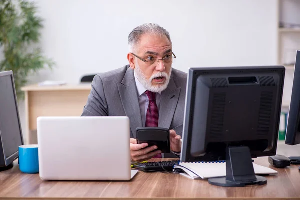 Vecchio capo maschio seduto sul desktop in ufficio — Foto Stock