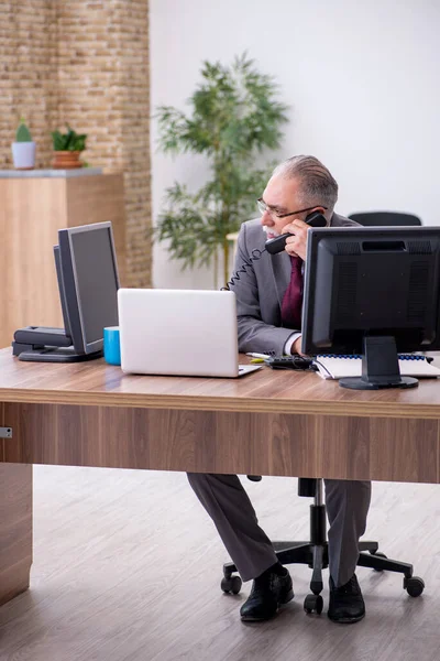 Velho chefe masculino sentado na área de trabalho no escritório — Fotografia de Stock