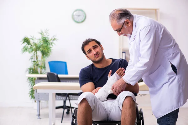 Jonge gewonde man bezoekt ervaren mannelijke arts traumatologis — Stockfoto