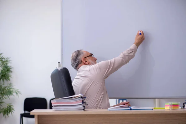 Старий вчитель чоловічої статі сидить у класі — стокове фото
