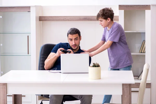 Joven padre y colegial jugando juegos de ordenador en casa — Foto de Stock