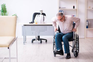 Tekerlekli sandalyedeki yaşlı adam ölü doktoru ziyaret ediyor.