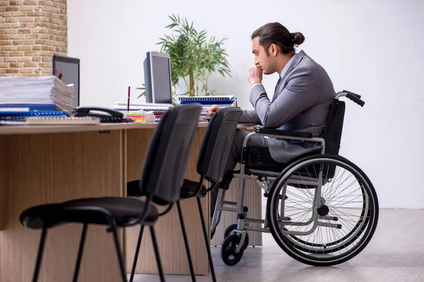Jonge mannelijke werknemer in een rolstoel op de werkplek — Stockfoto