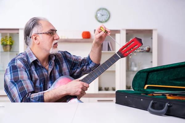 Seniorchef repariert Musikinstrumente zu Hause — Stockfoto