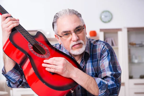 Senior mannelijke reparateur die thuis muziekinstrumenten repareert — Stockfoto