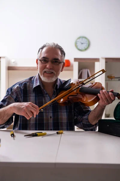 Starší opravář mužského pohlaví opravuje doma hudební nástroje — Stock fotografie