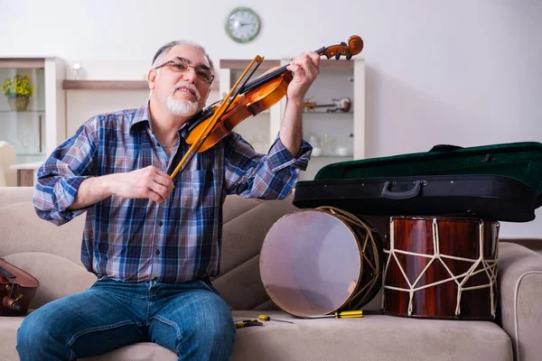 Riparatore anziano di sesso maschile che ripara strumenti musicali a casa — Foto Stock