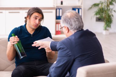 Alkol bağımlısı genç adam yaşlı erkek psikoloğu ziyaret ediyor.