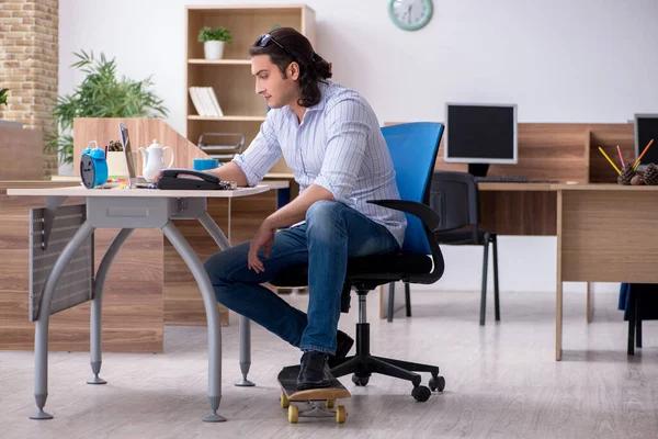 Jeune employé masculin avec skateboard dans le bureau — Photo
