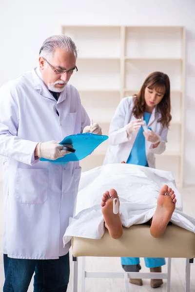 Police coroner examining dead body corpse in morgue — Stock Photo, Image