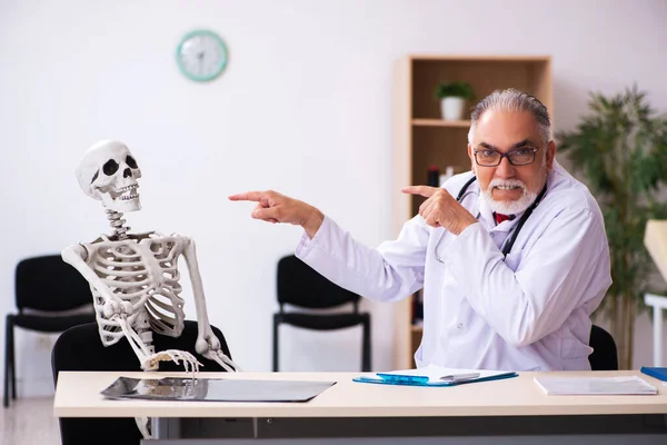 Alte männliche Arzt und Skelett-Patient in der Klinik — Stockfoto