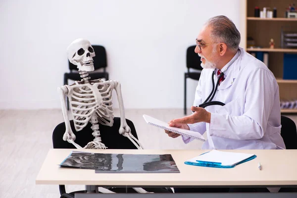 Vieux médecin masculin et patient squelette à la clinique — Photo