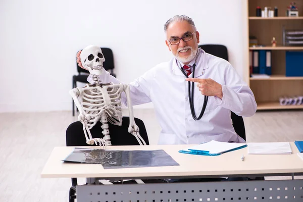 Klinikteki yaşlı erkek doktor ve iskelet hastası. — Stok fotoğraf