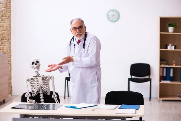 Oude mannelijke dokter en skelet patiënt in de kliniek — Stockfoto