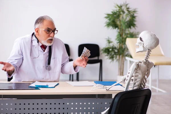 Oude mannelijke dokter en skelet patiënt in de kliniek — Stockfoto