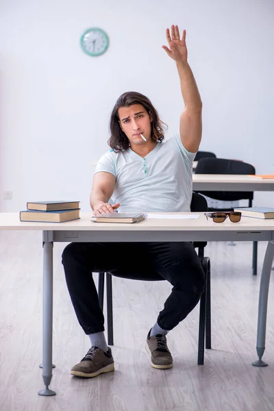 Jonge mannelijke student die sigaretten rookt in de klas — Stockfoto