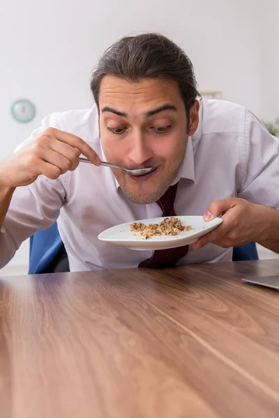 Голодный работник-мужчина ест гречку во время перерыва — стоковое фото