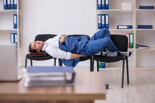 Ung manlig anställd sover på kontoret på stolar — Stockfoto