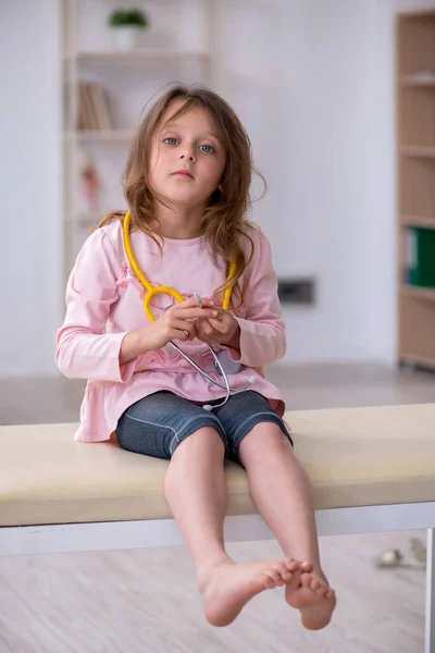 Petite fille tenant stéthoscope attendant un médecin à la clinique — Photo