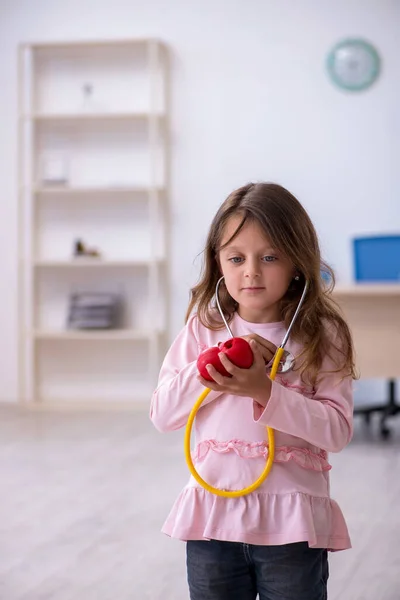 Petite fille tenant stéthoscope attendant un médecin à la clinique — Photo