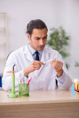 Genç erkek doktor stomatolojist klinikte çalışıyor.