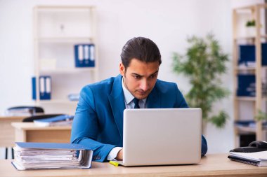 Genç bir erkek işçi ve ofiste çok fazla iş var.