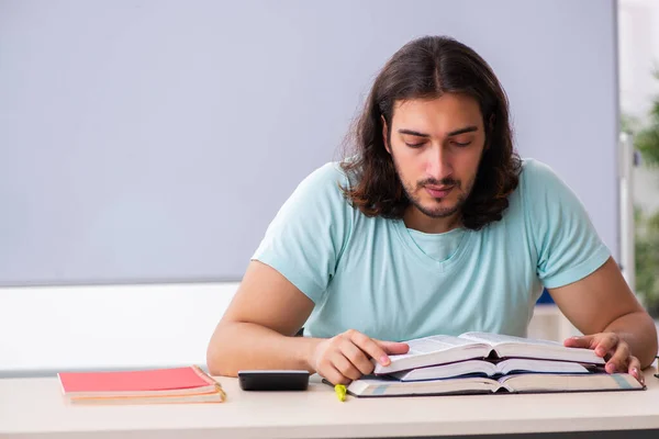 Jonge mannelijke student bereidt zich voor op examens in de klas — Stockfoto