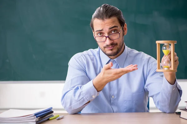 Ung manlig lärare i klassrummet i time management koncept — Stockfoto